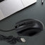 A black wired optical mouse from Compshop with its USB cable clearly visible.