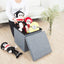A stylish grey foldable storage stool with a comfortable cushion top, perfect for living room organization.