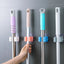 Self-adhesive mop holder securely mounted on a white wall, showcasing its compact design.