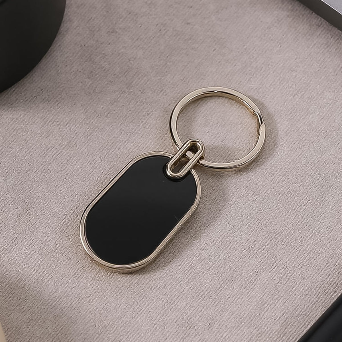 Oval metal keychain with glossy black center and polished silver frame Main image