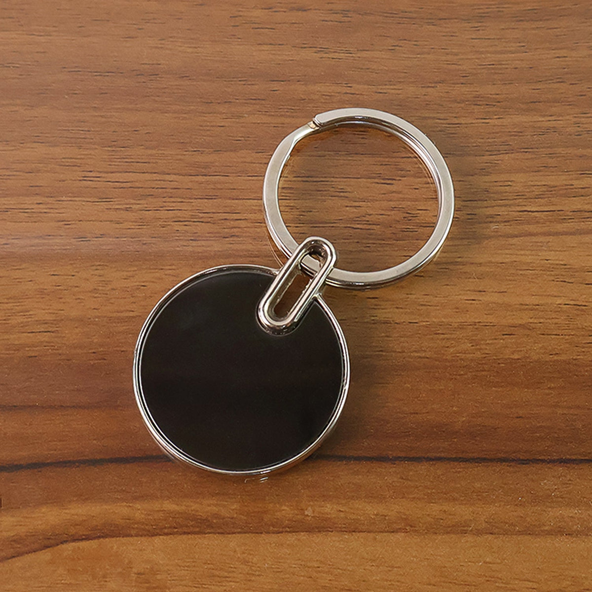 Black round metal keychain with polished chrome finish and smooth black charm Main image