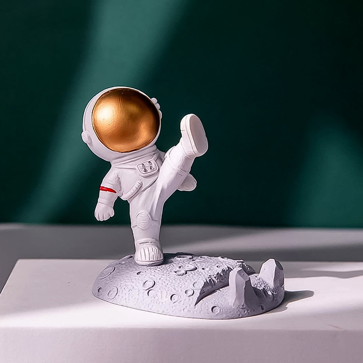 Astronaut Phone Holder (kicking leg design) on a wooden desk, holding a smartphone. Main image