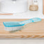 Scrubbing brush with plastic handle cleaning a pair of white shoes.