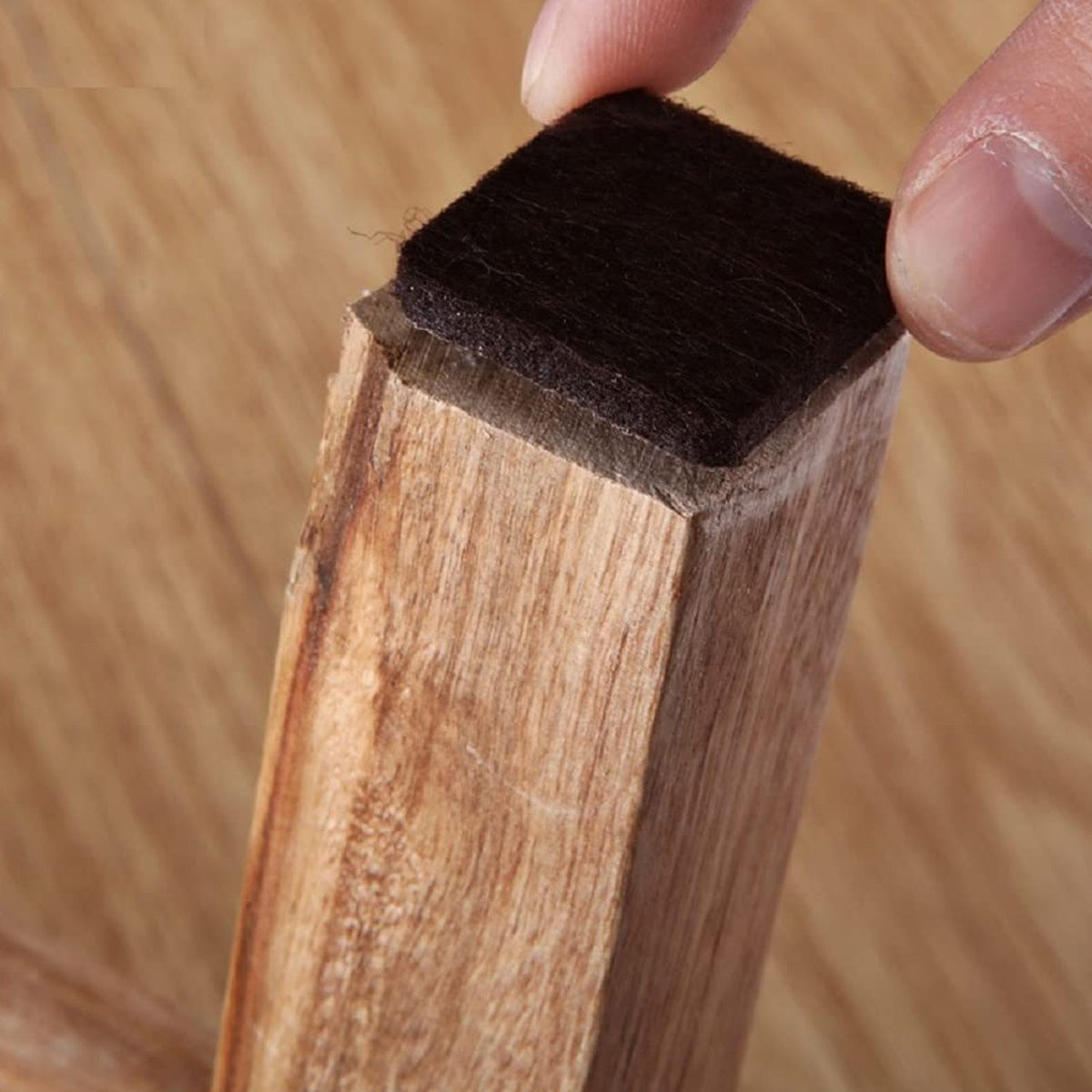 Square self-adhesive furniture pad for floor protection on a wooden surface. Main image