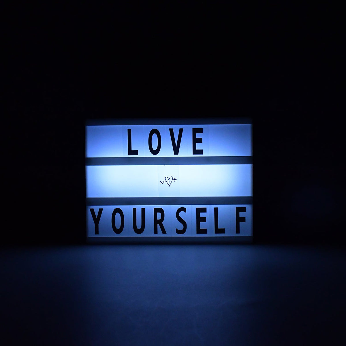 Black Mini A6 Cinematic Light Box displaying a custom message on a wooden surface. Main image