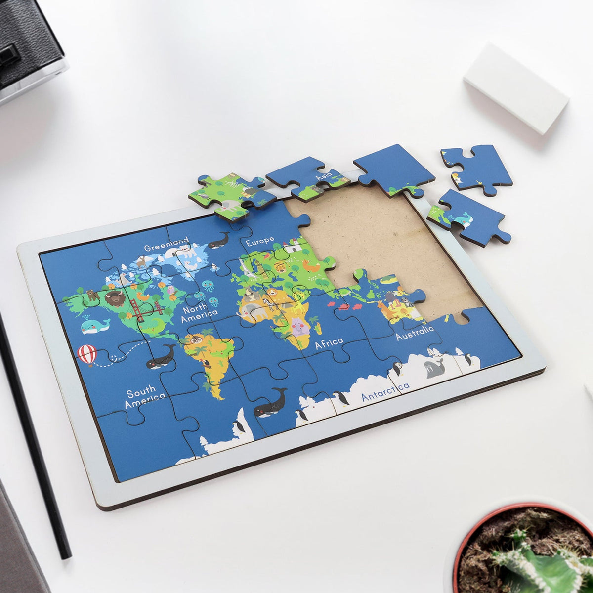 Completed wooden world map puzzle showing continents, animals, and landmarks. Main image
