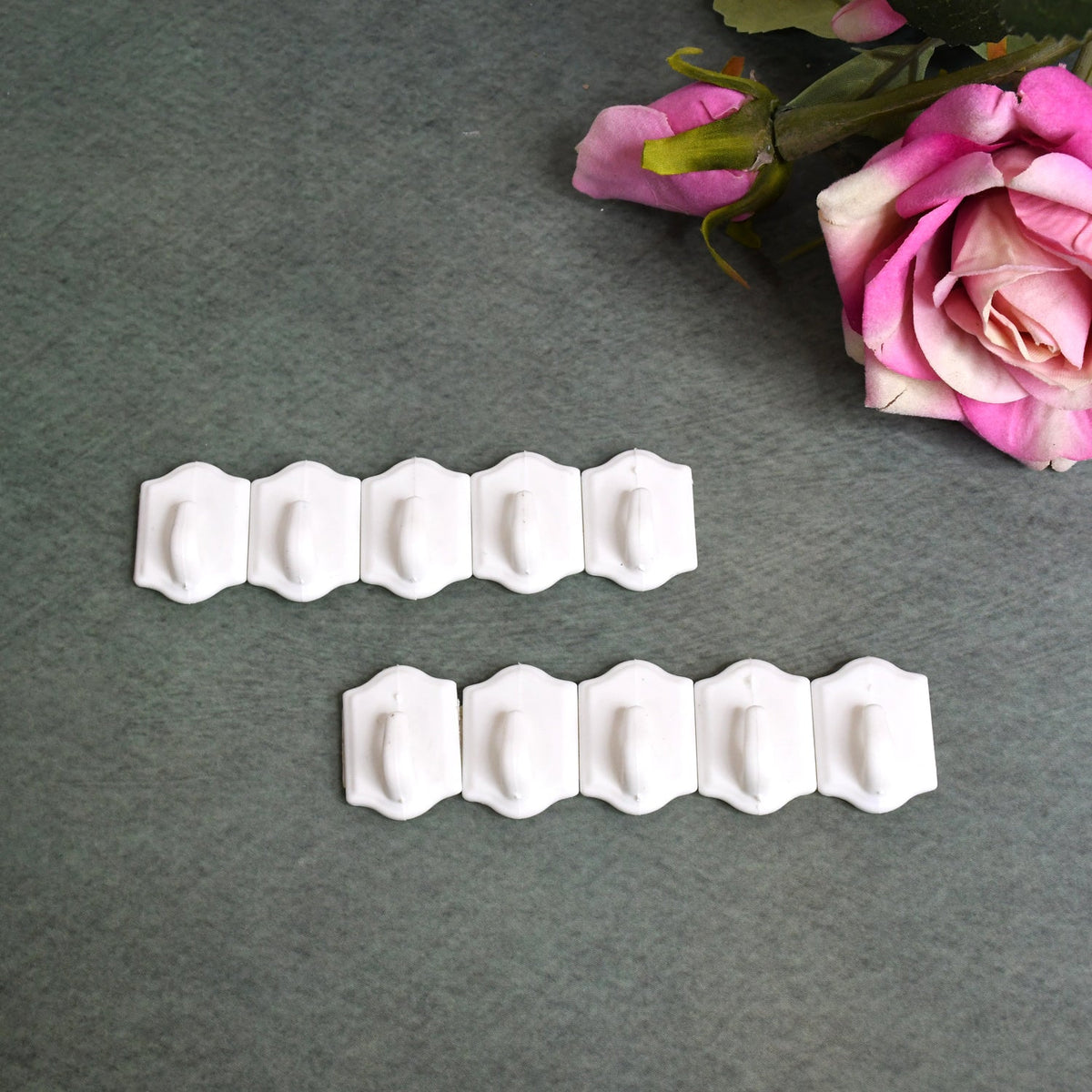 Set of 10 white plastic adhesive wall hooks for drill-free hanging. Main image