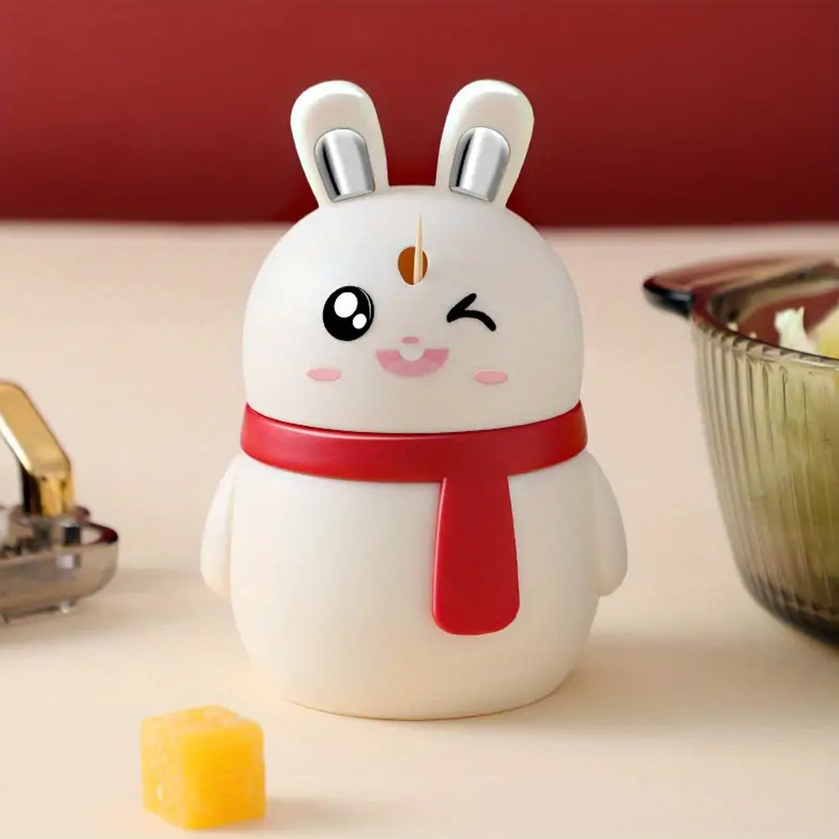 A red rabbit toothpick dispenser with an automatic press mechanism on a wooden table. Main image