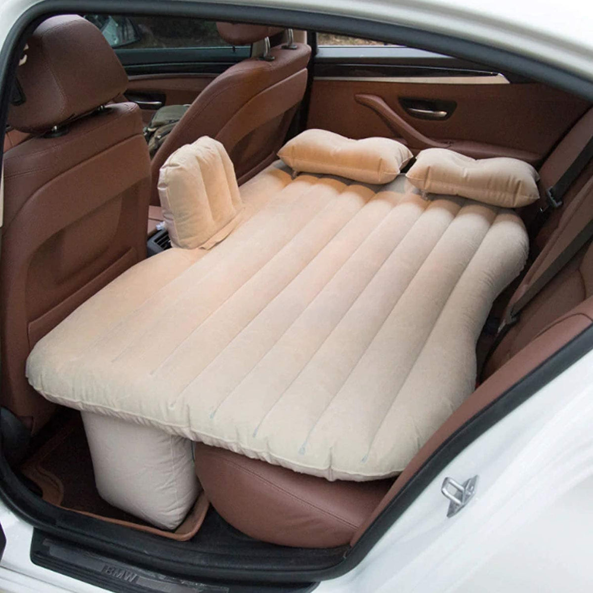 Inflatable car bed with two pillows and pump set up in a car's back seat. Main image