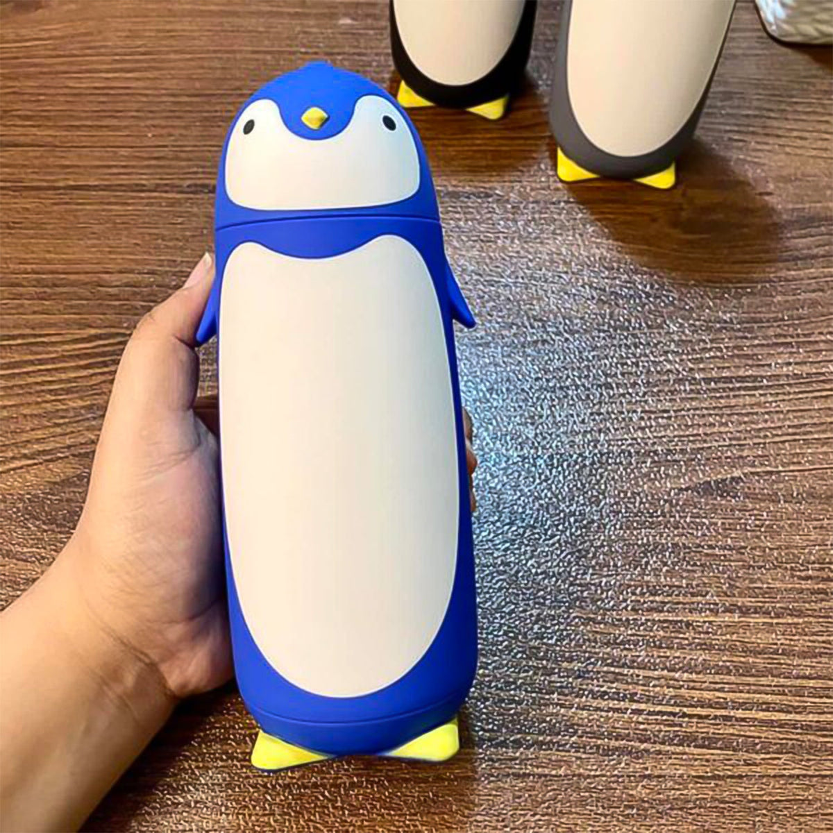 Blue and black penguin water bottle with cartoon design side view Main image