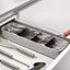 An empty, grey plastic cutlery tray with multiple compartments for kitchen drawer organisation.