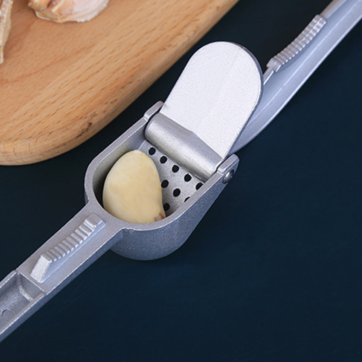 Aluminum garlic press on a kitchen counter, ready for use. Main image