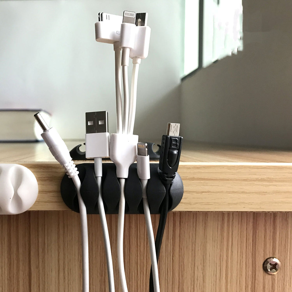 Cable organiser clips in black, shown holding multiple wires neatly on a desk. Main image