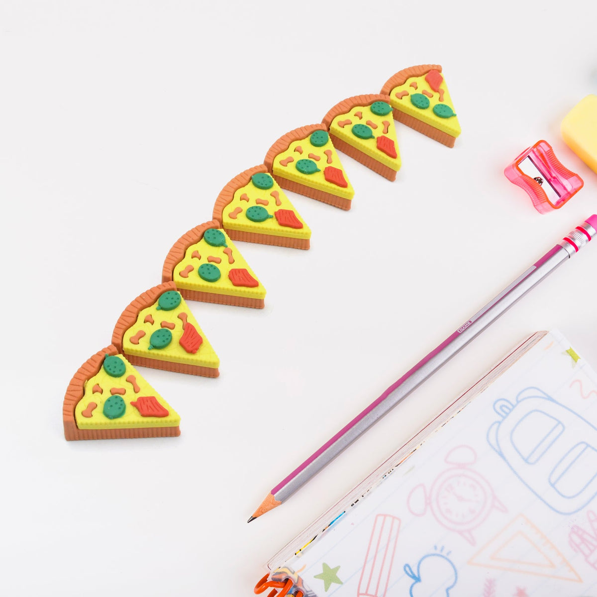 A set of seven colorful 3D pizza slice erasers arranged on a clean white surface. Main image