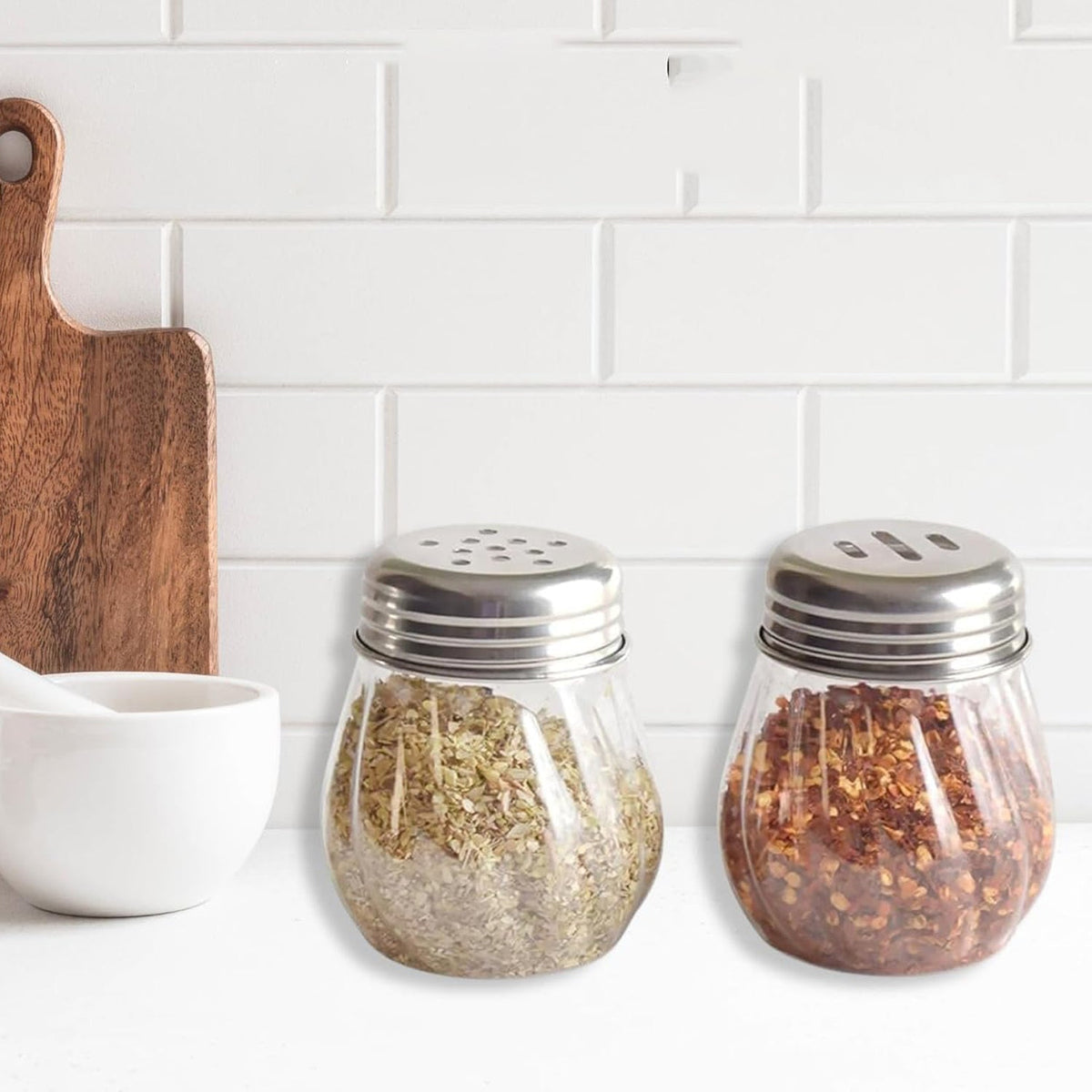 Oregano & Chilli Flakes Dispenser Set with clear plastic body and stainless steel lids on kitchen counter Main image