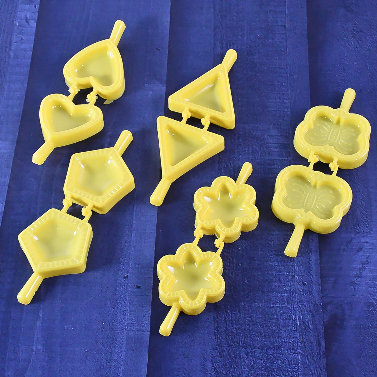 Plastic cookie cutter set with assorted shapes on a wooden table, ready for baking. Main image