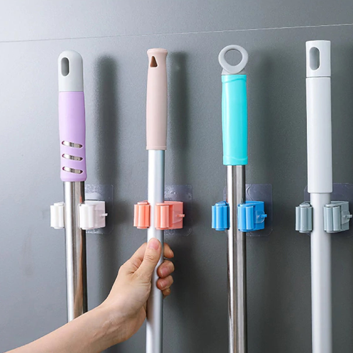 Self-adhesive mop holder securely mounted on a white wall, showcasing its compact design. Main image