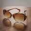 Fashionable oversized sunglasses for women with gradient lenses and gold floral temples.
