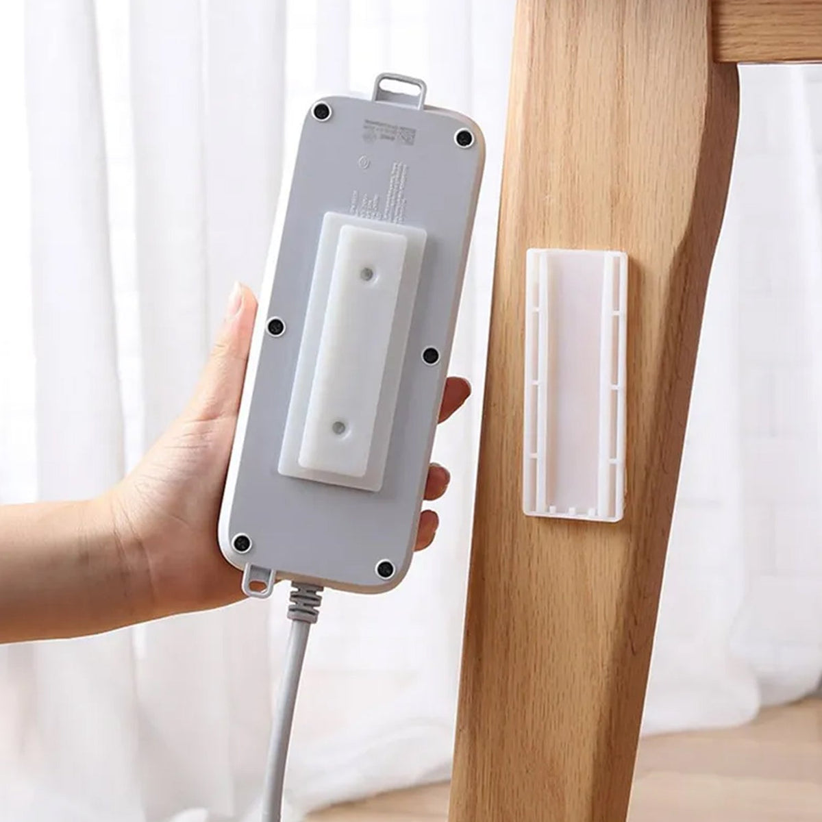 Self Adhesive Plug Organizer on a white wall, neatly holding a power strip. Main image