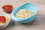 Large plastic rice bowl strainer in use, showing grains being washed.