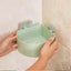 Self adhesive corner shelf installed in a modern bathroom.