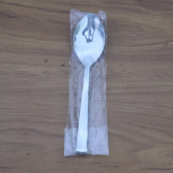 Stacked stainless steel dining spoons placed in a home kitchen setting