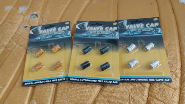 A silver aluminium valve stem cap resting gently on a smooth surface.