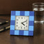 Modern square table clock with a bold frame, displayed on a desk.
