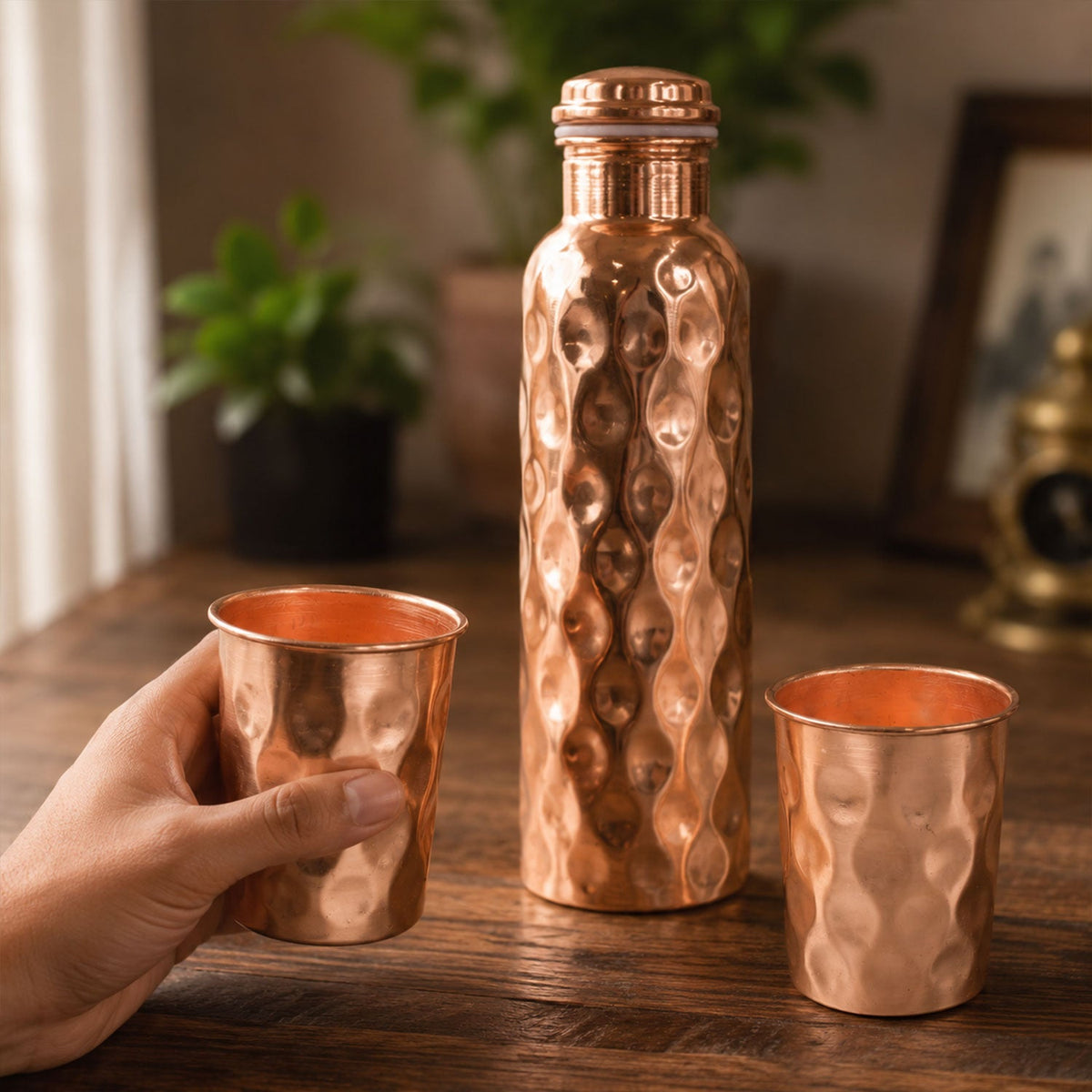 Diamond cut copper water bottle set with two matching glasses on a light background. Main image