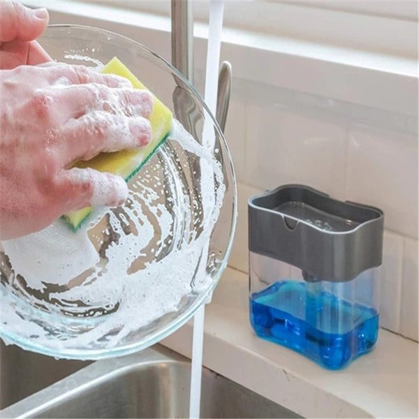 A grey 2-in-1 soap dispenser with a clean white sponge on a kitchen countertop. Main image