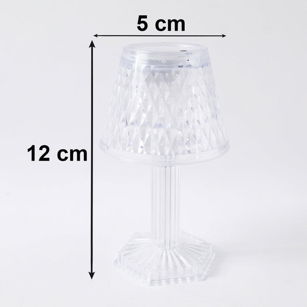 Small crystal table lamp creating a warm, ambient glow in a dark room.
